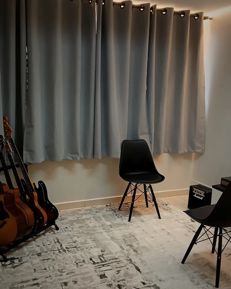 Sala de aula da Verso, com violões e guitarras nos suportes, amplificador e cadeiras